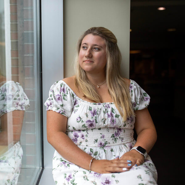 Woman sits on windowsill and looks out window