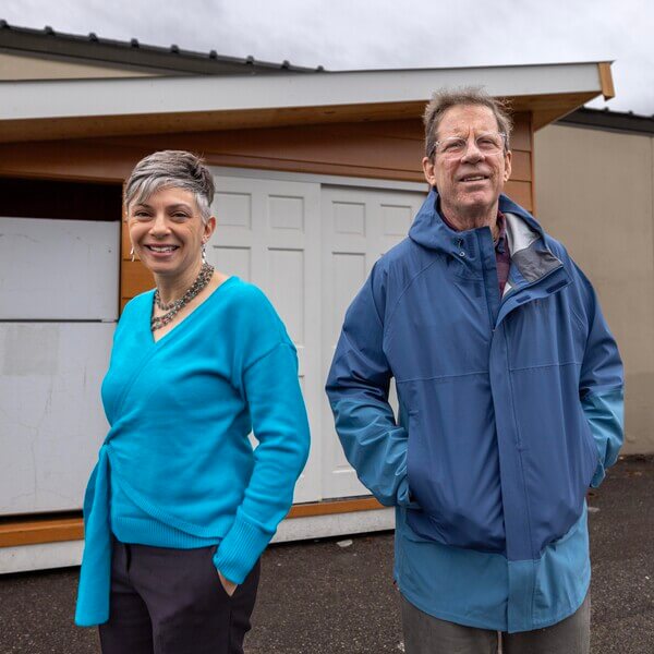 A man and woman stand in front of an outdoor refrigerator