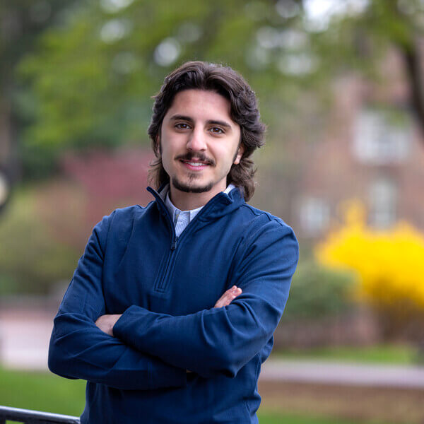 Man with beard stands with arms crossed