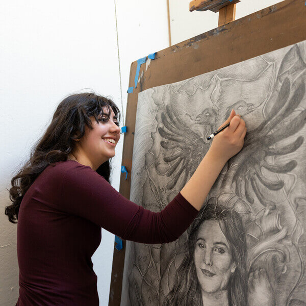 Sophie Sundaram working on a black and white drawing at an easel