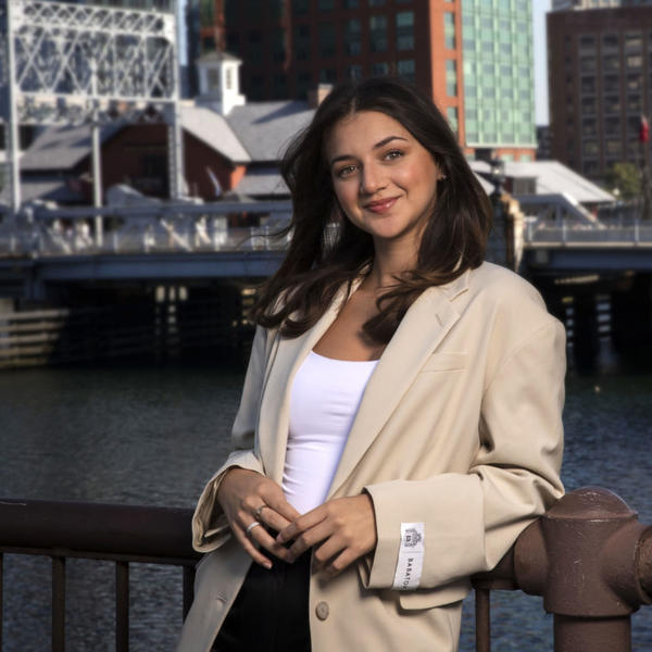 Woman leans against railing along a city harbor.