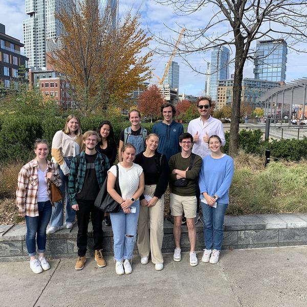 A group of men and women pose in a group in front of grennery.
