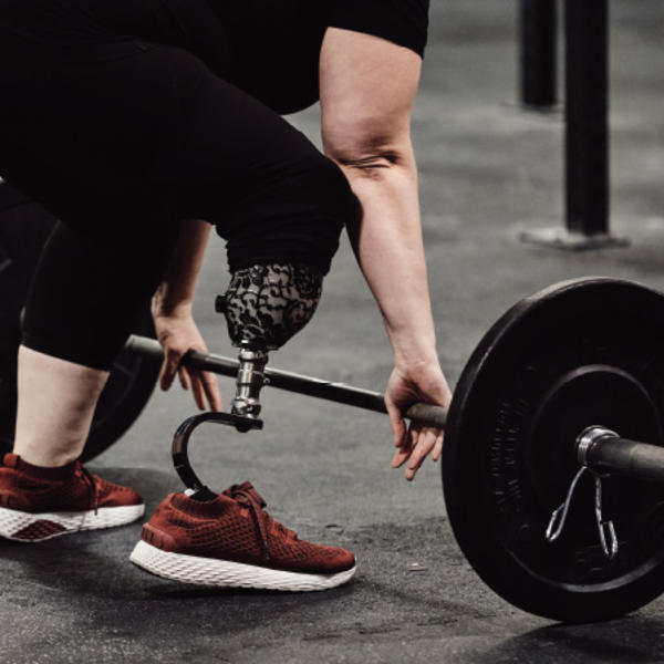 Melissa DeChellis reaches for a barbell, showing her prosthetic leg