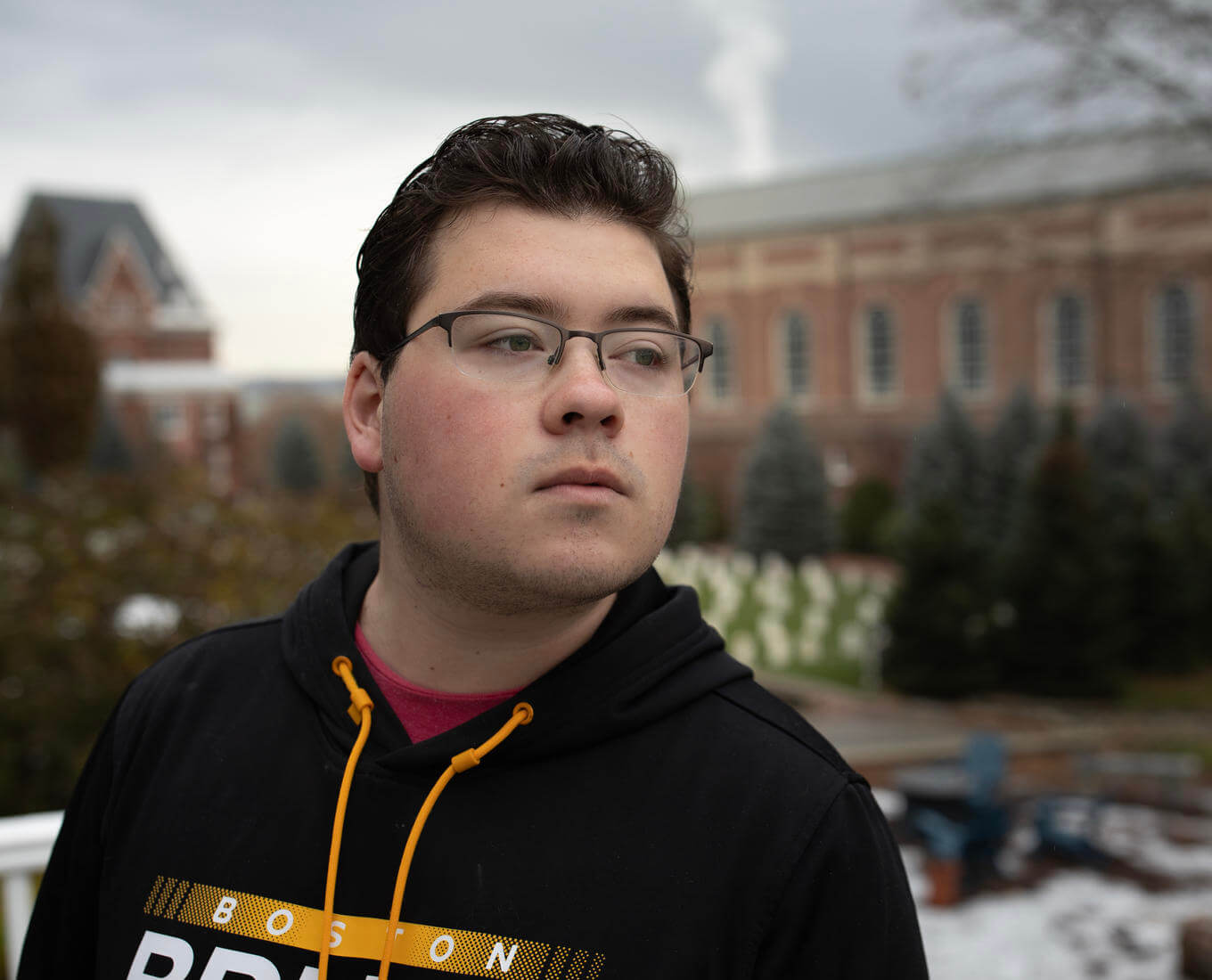 Male student in black sweatshirt looks over his left shoulder. 