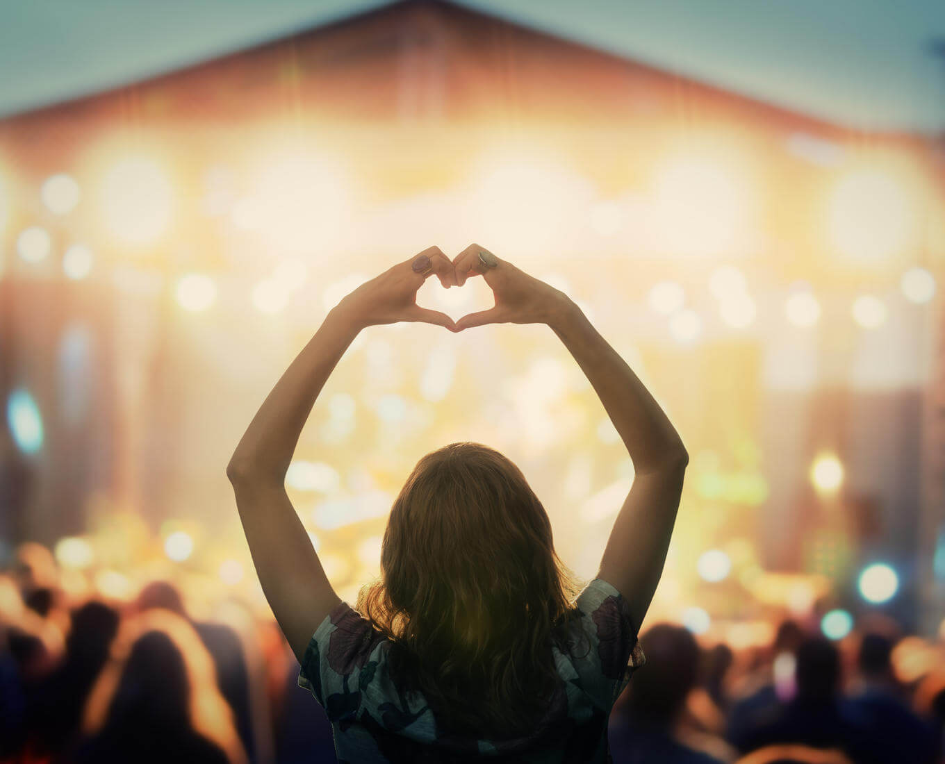Girl making a heart-hand symbol for her favorite band. Photo credit: astrosystem