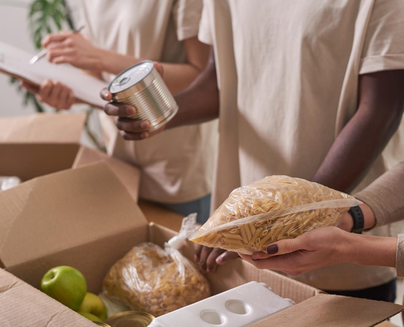 People holding nonperishable foods to put in boxes for distribution.