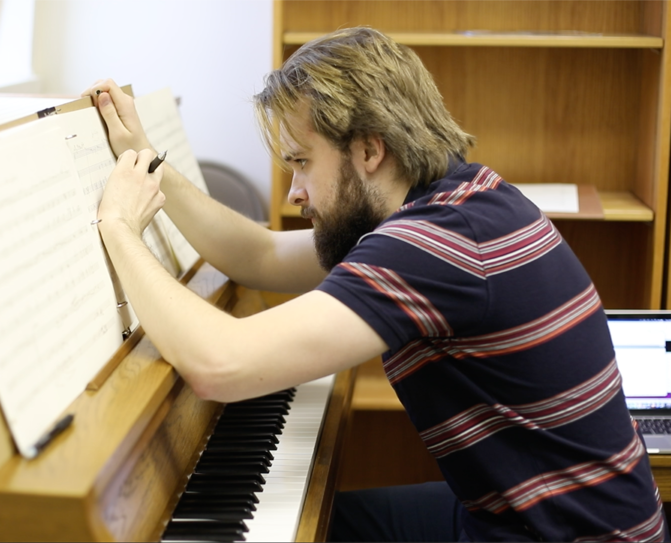 Student hunches over piano and writes sheet music