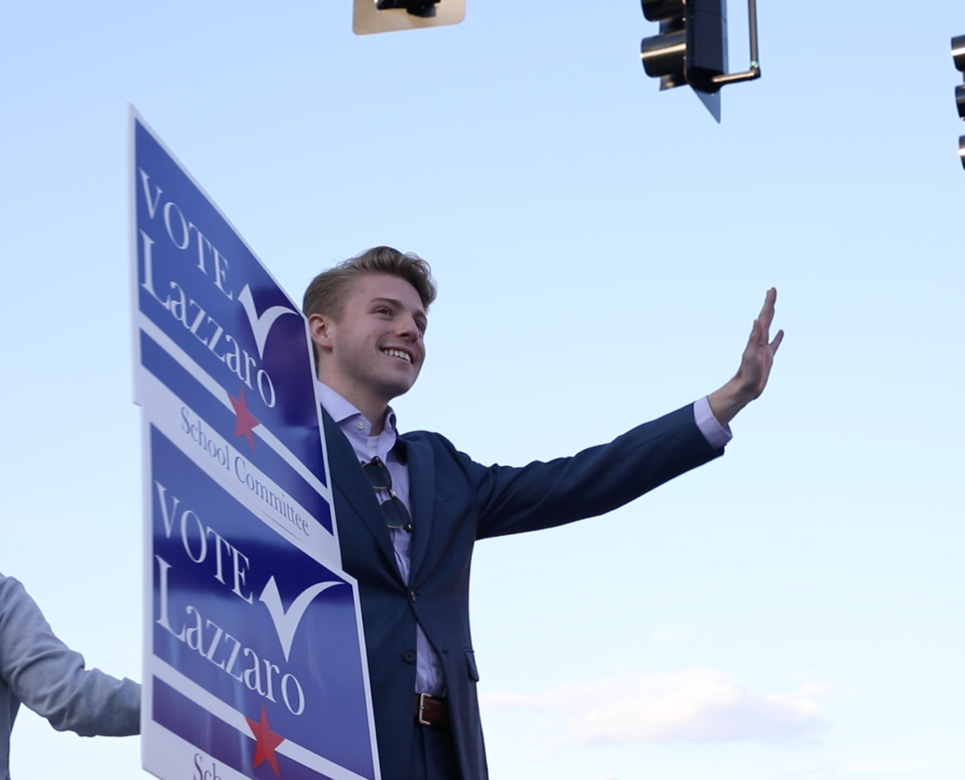 Nick Lazzaro waves to traffic and shows off his campaign sign