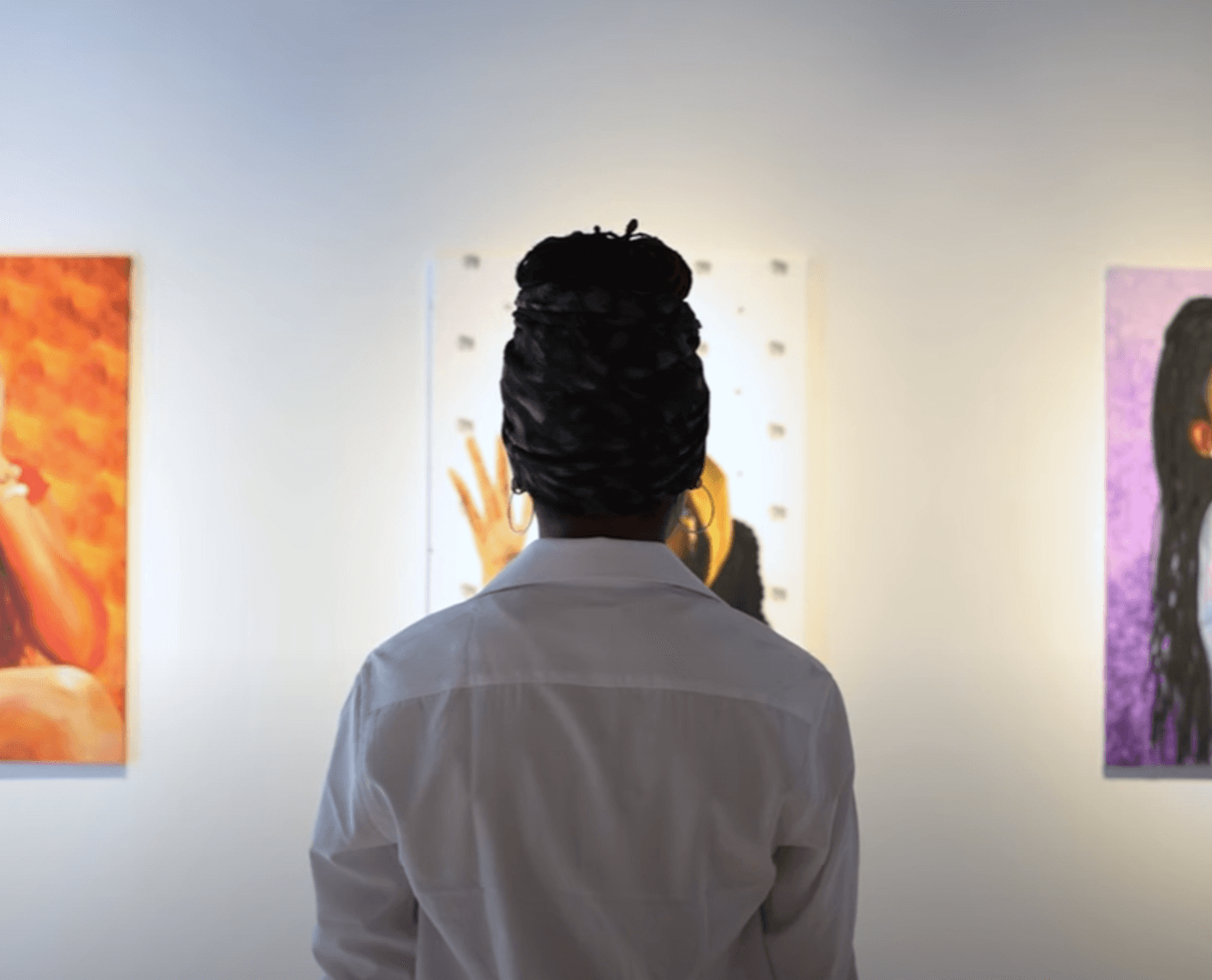 A woman stands between two paintings