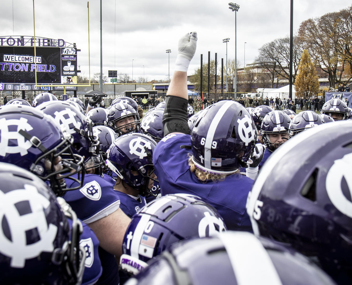 A man with his arm extended standing amid dozens of football helmets