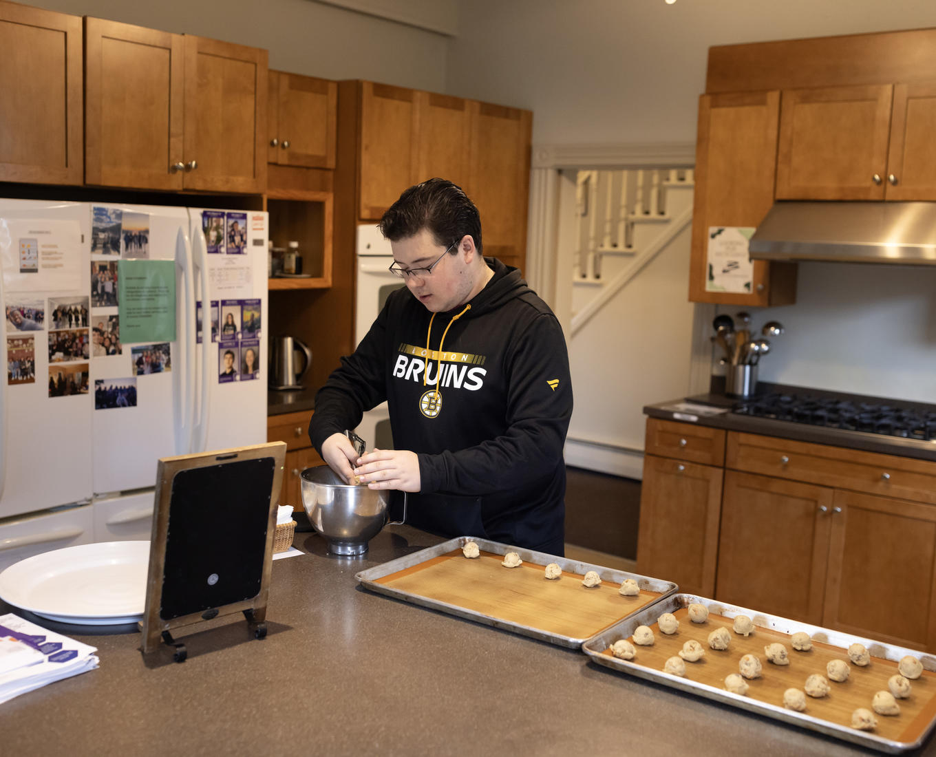 Man scoops cookie dough onto baking sheet