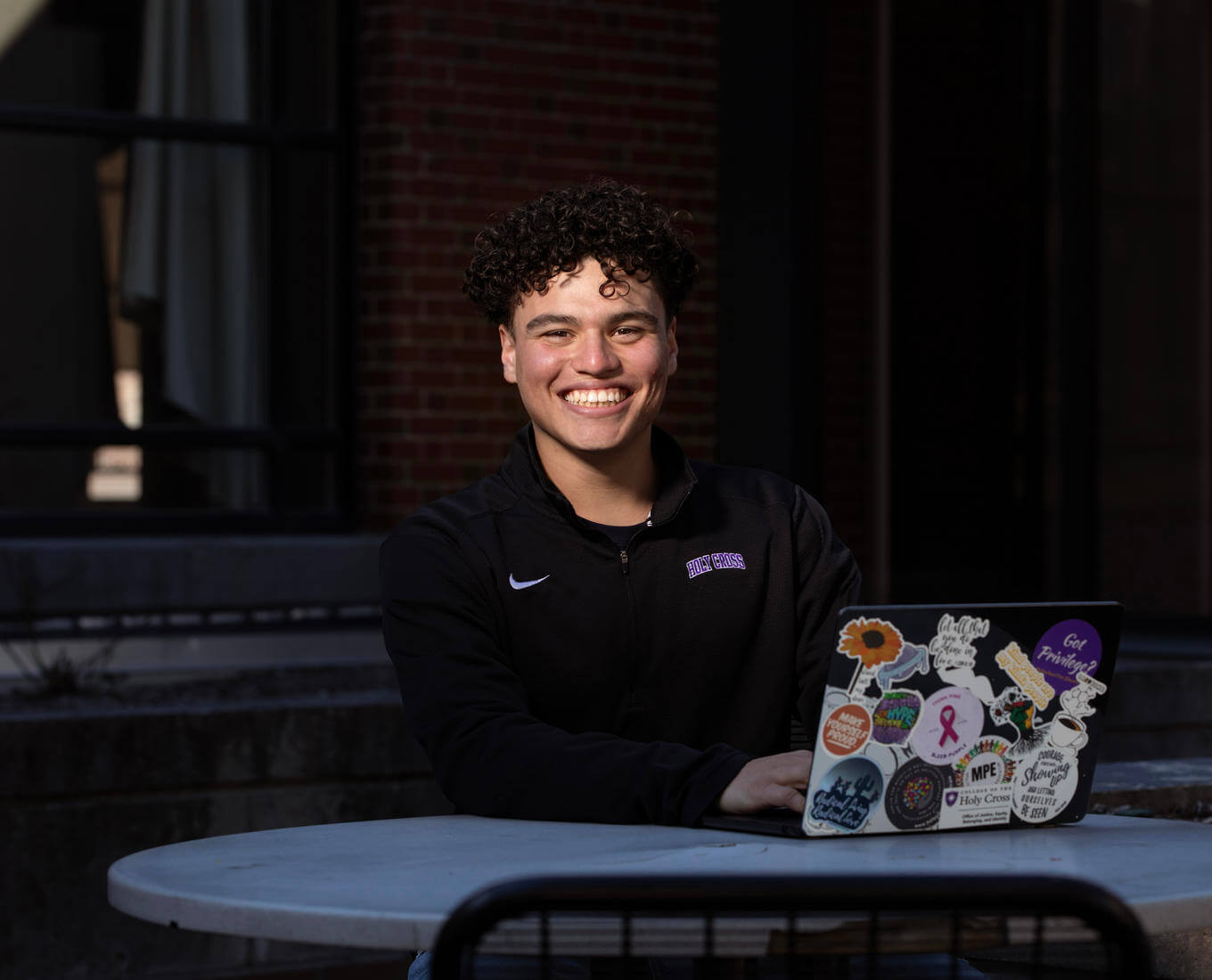 Young Hispanic male student sitting at a table with a laptop.