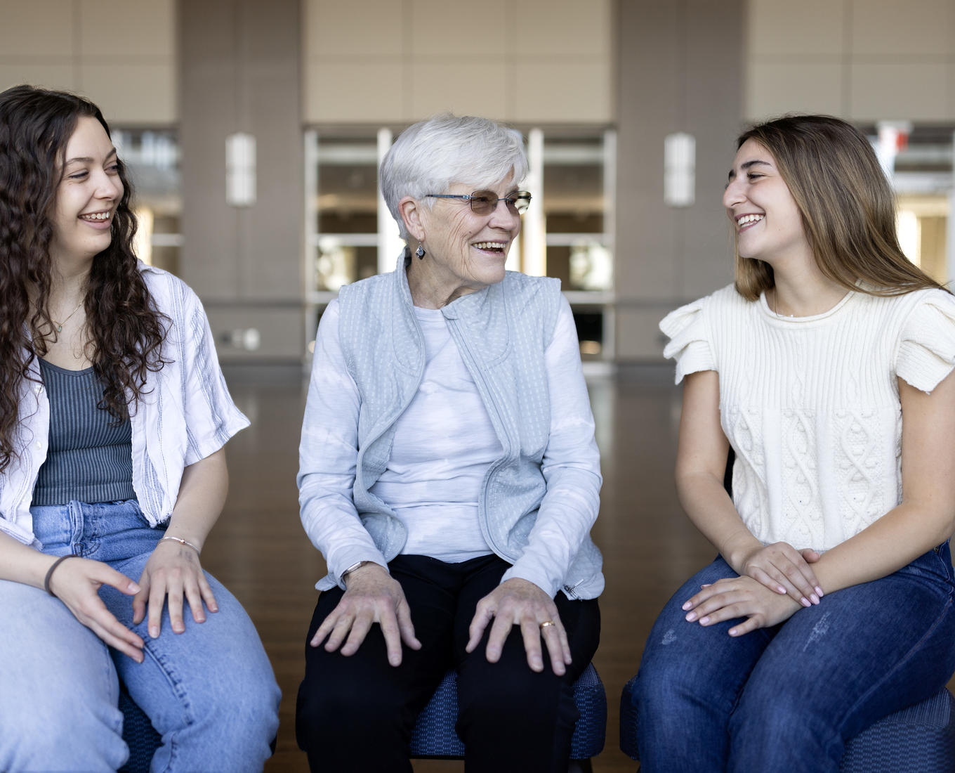 Two female graduating seniors talk with a female former professor.