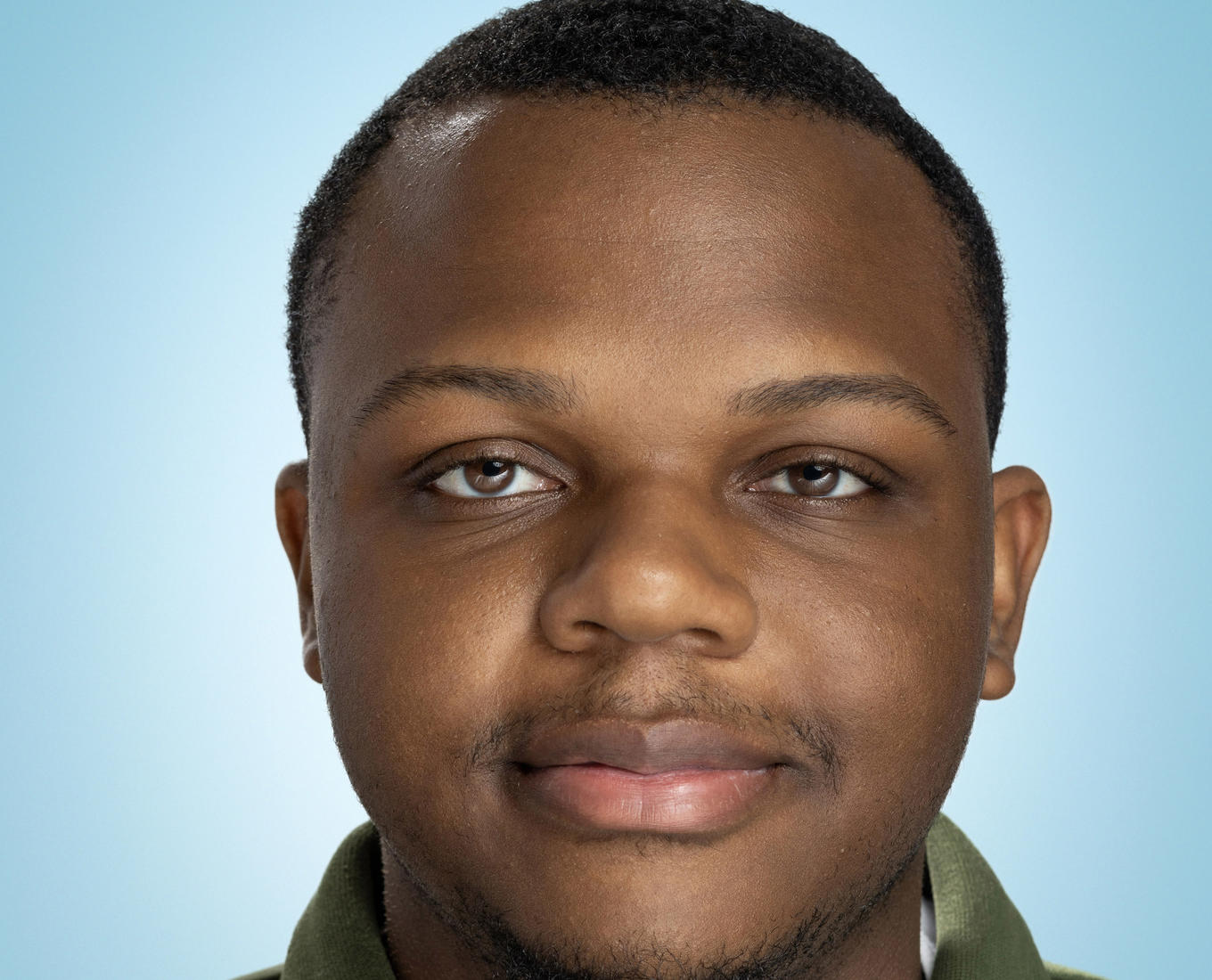A young man smiles wearing a collard shirt 