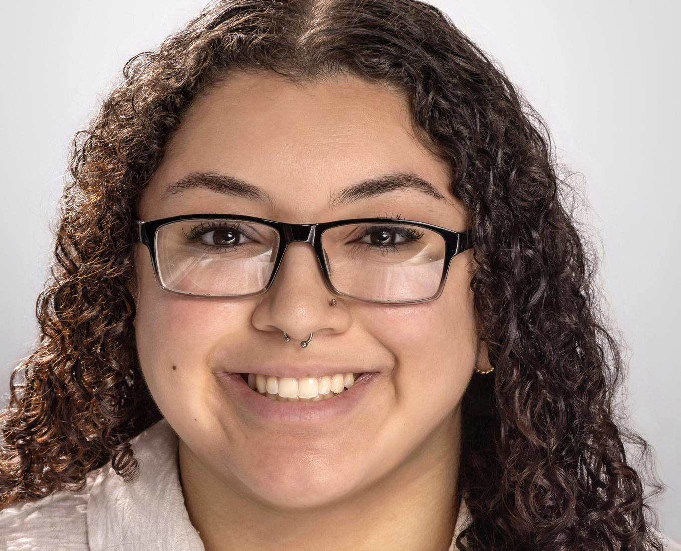A smiling young woman with glasses and curly hair