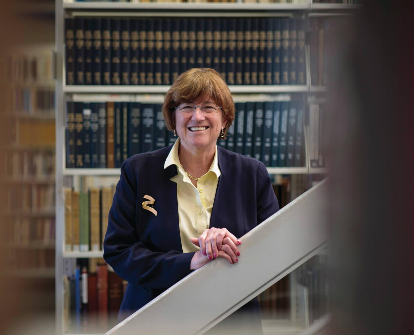 Smiling woman stands near a shelf of books