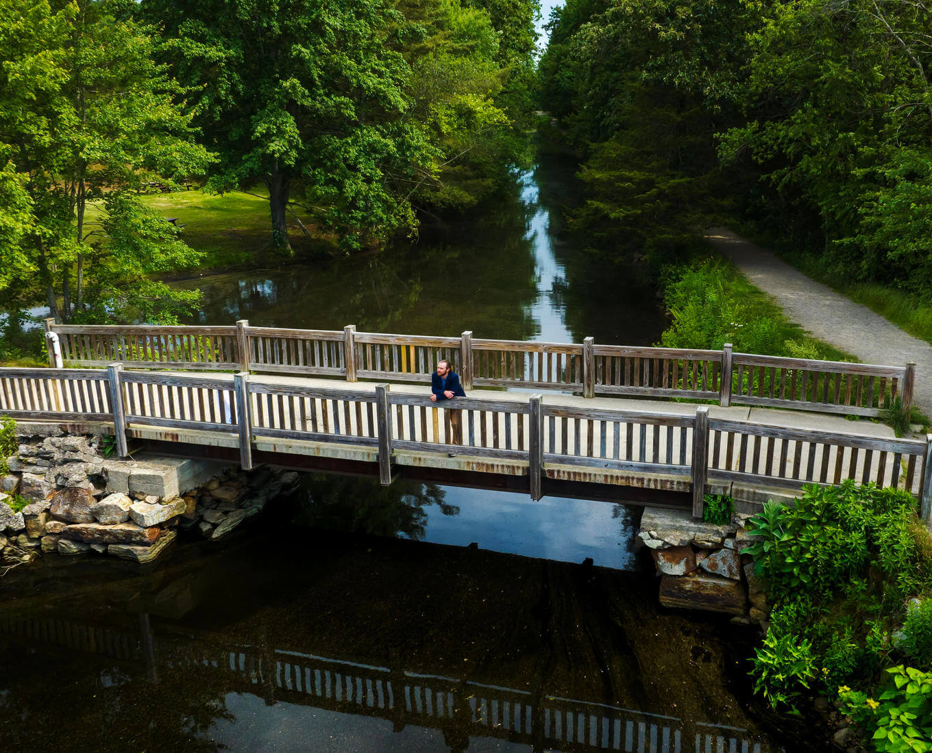 Man stands on bridge over a river.