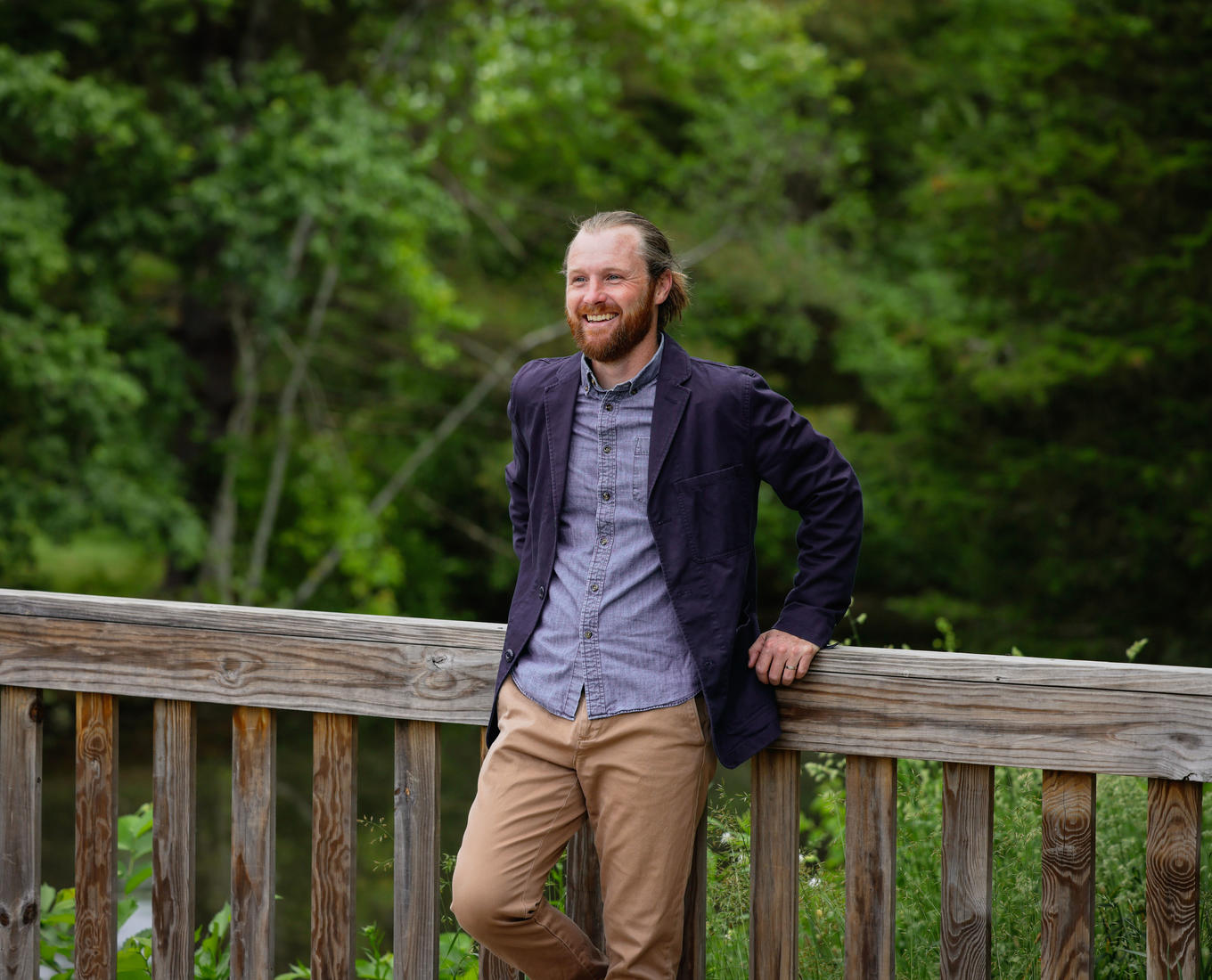 Bearded man leans against a bridge railing