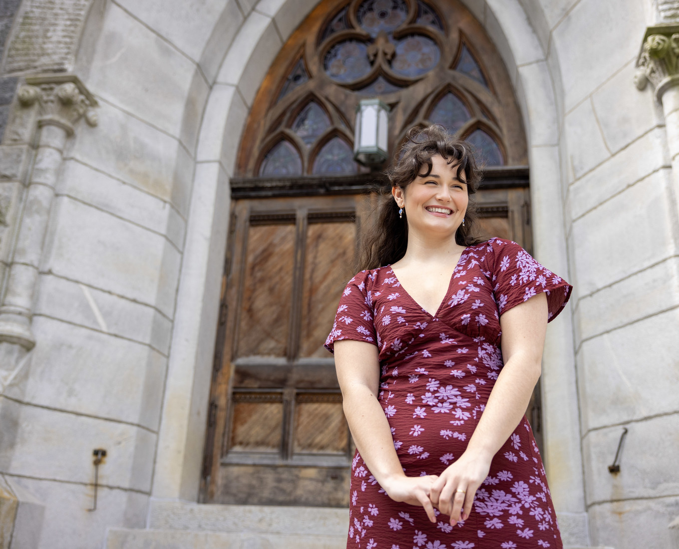 Smiling woman stands on church outside stairs