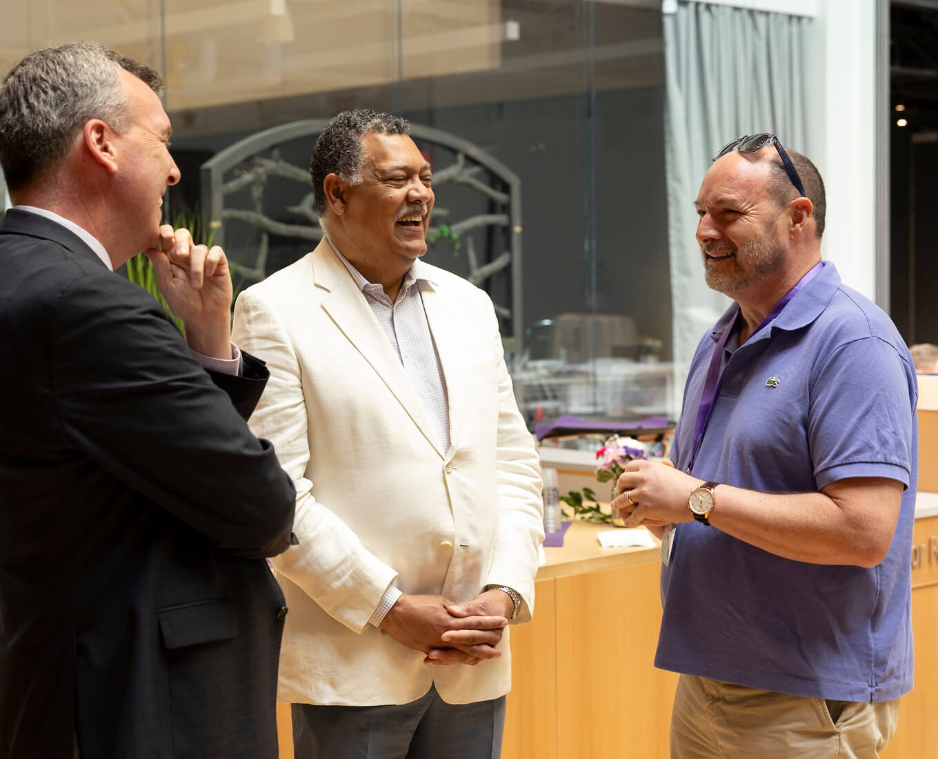 three men talking at a reception
