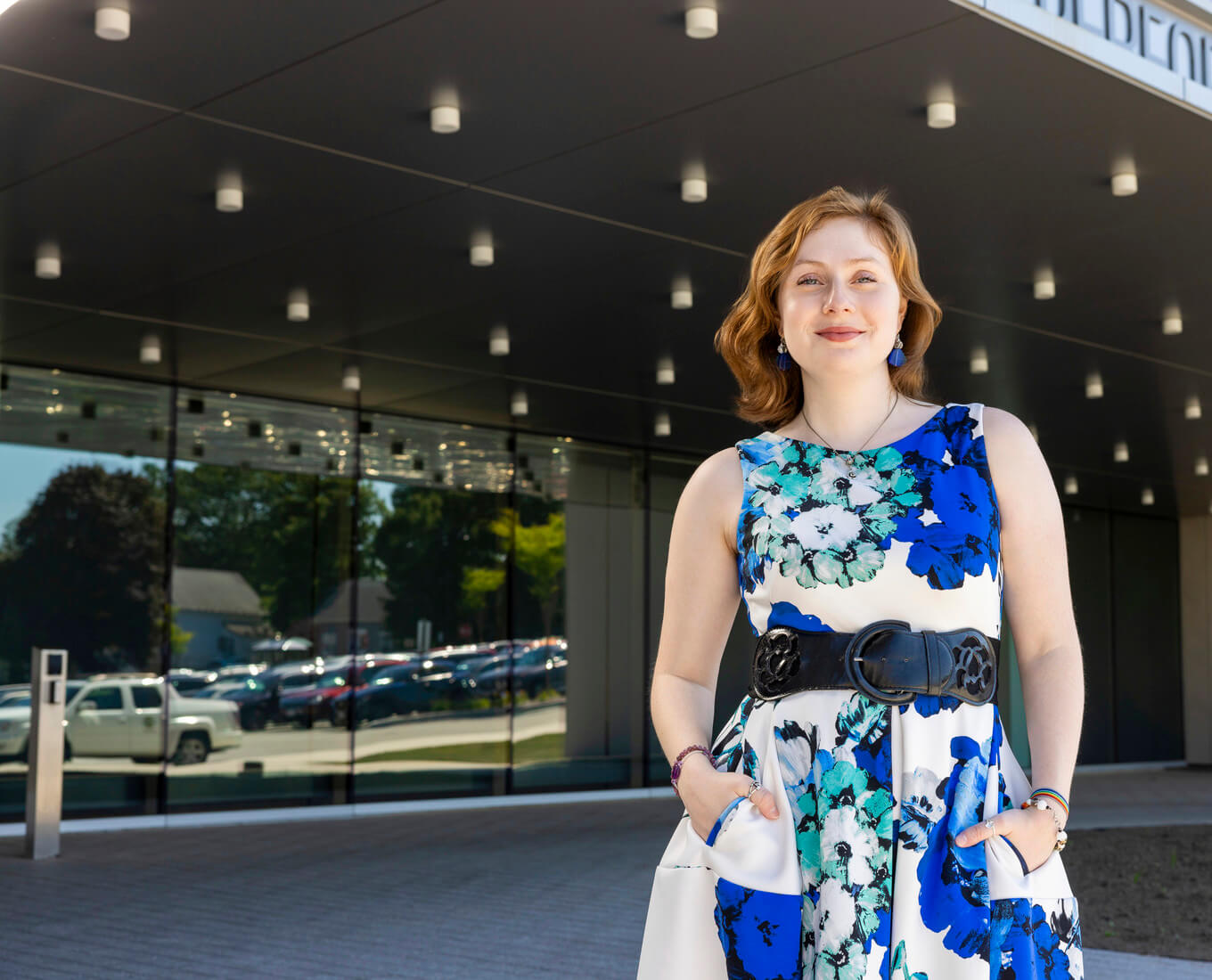 Woman in sleeveless dress stands in front of building