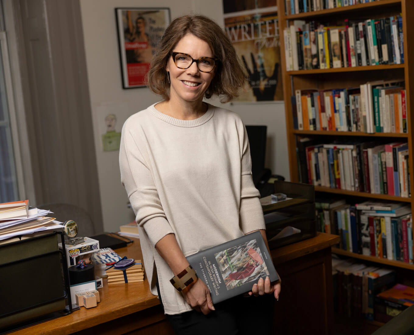 woman with glass in office holding a book