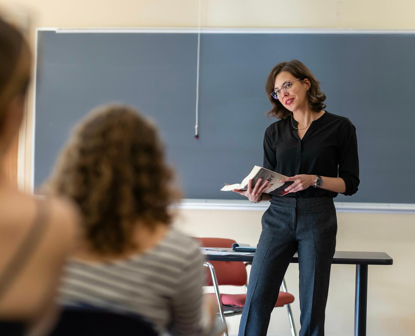 woman in front of a blackboard with poetry book