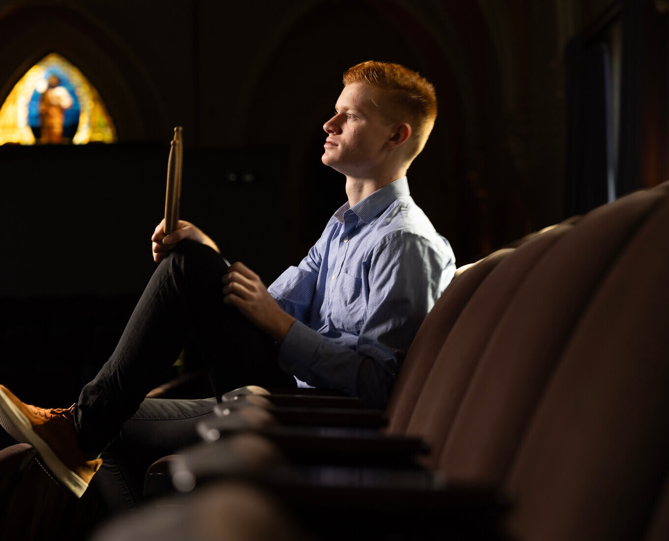 Side profile of man sitting holding drumsticks