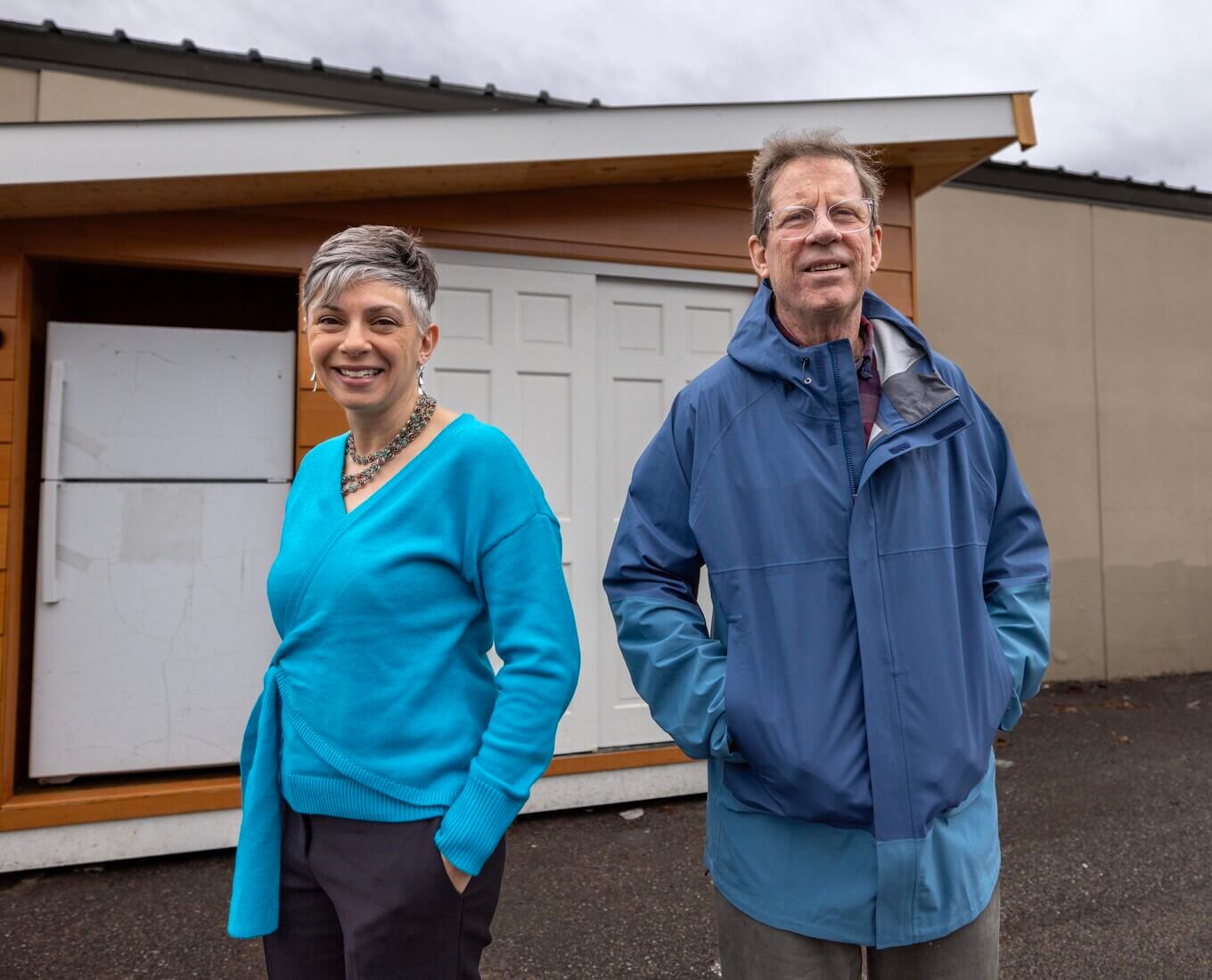 A man and woman stand in front of an outdoor refrigerator
