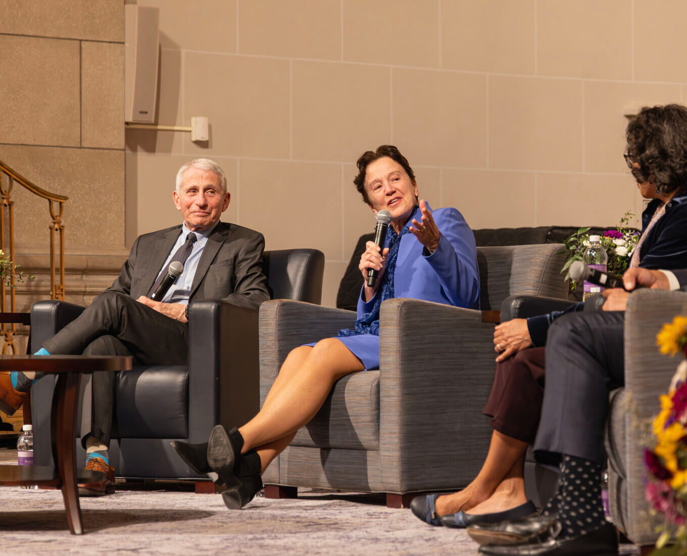 Seated woman speaks into microphone flanked by three other seated people