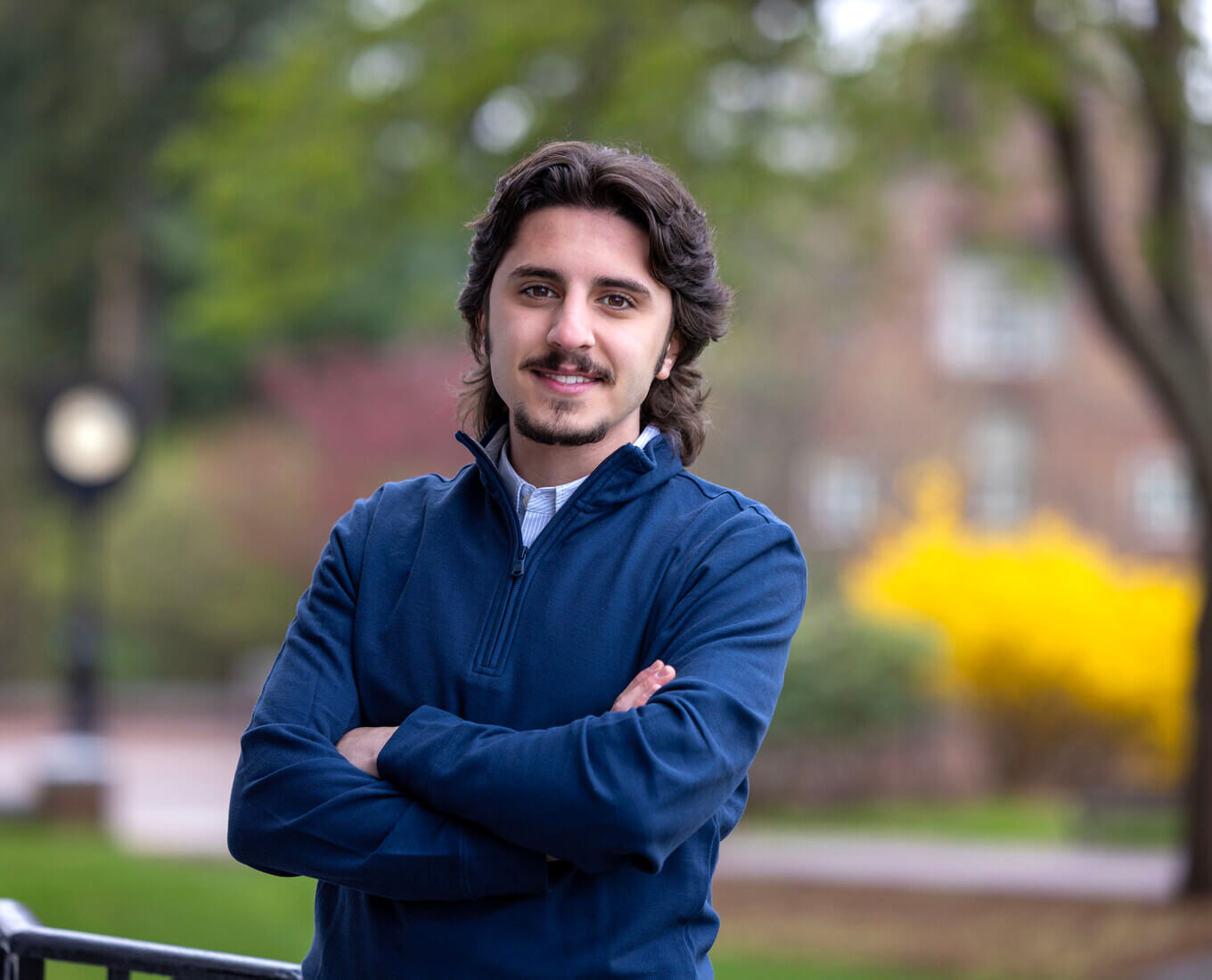 Man with beard stands with arms crossed