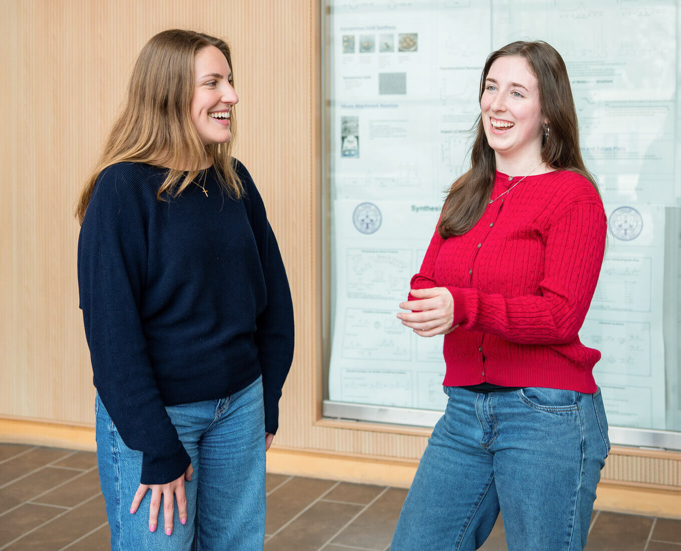 Two women in conversation in front of a whiteboard.