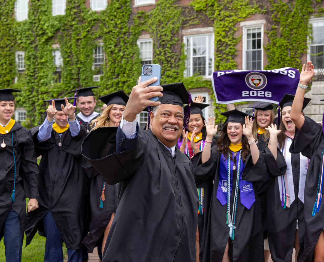 President Rougeau taking a selfie with graduates in front of Fenwick Hall
