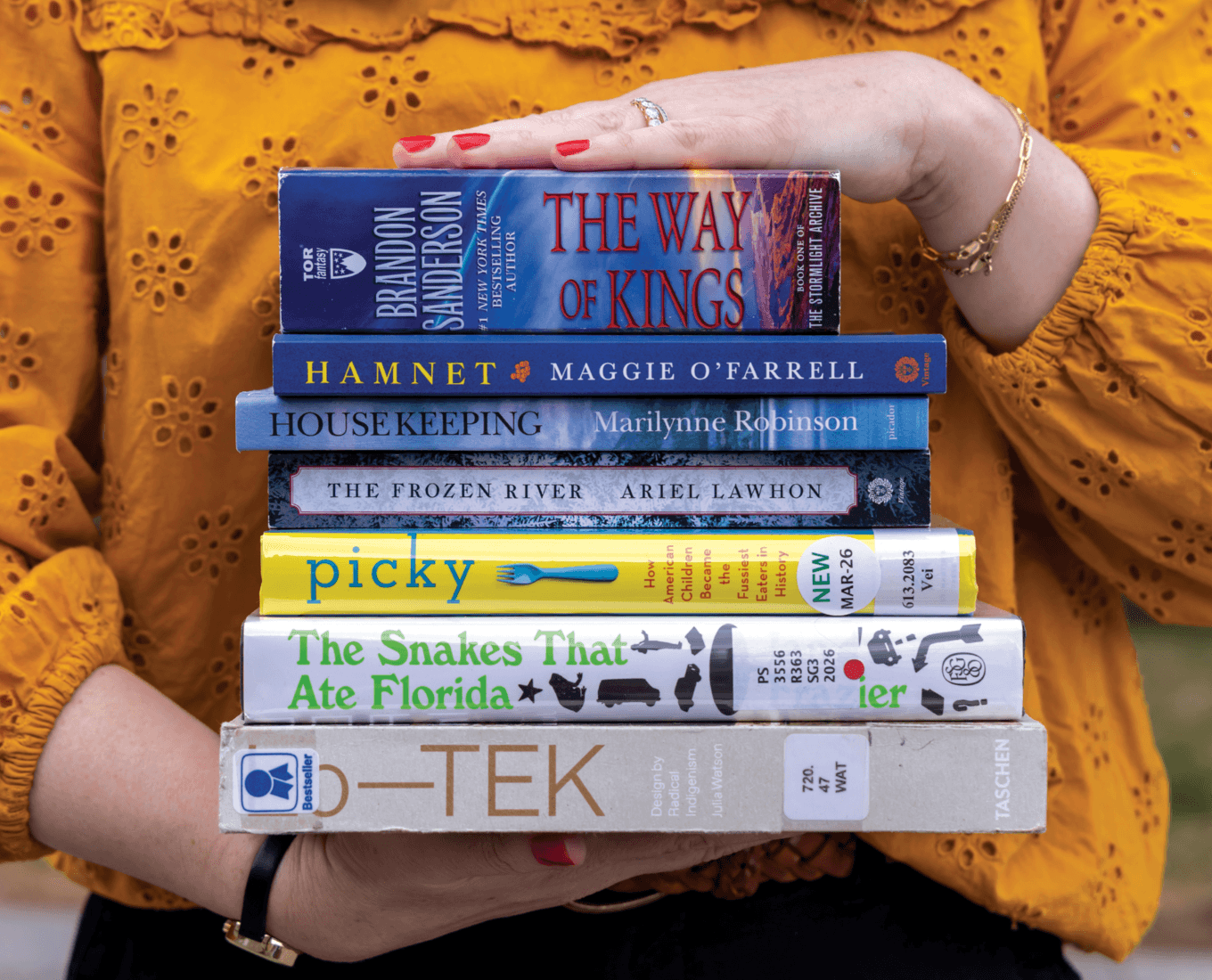 Hands holding a stack of books