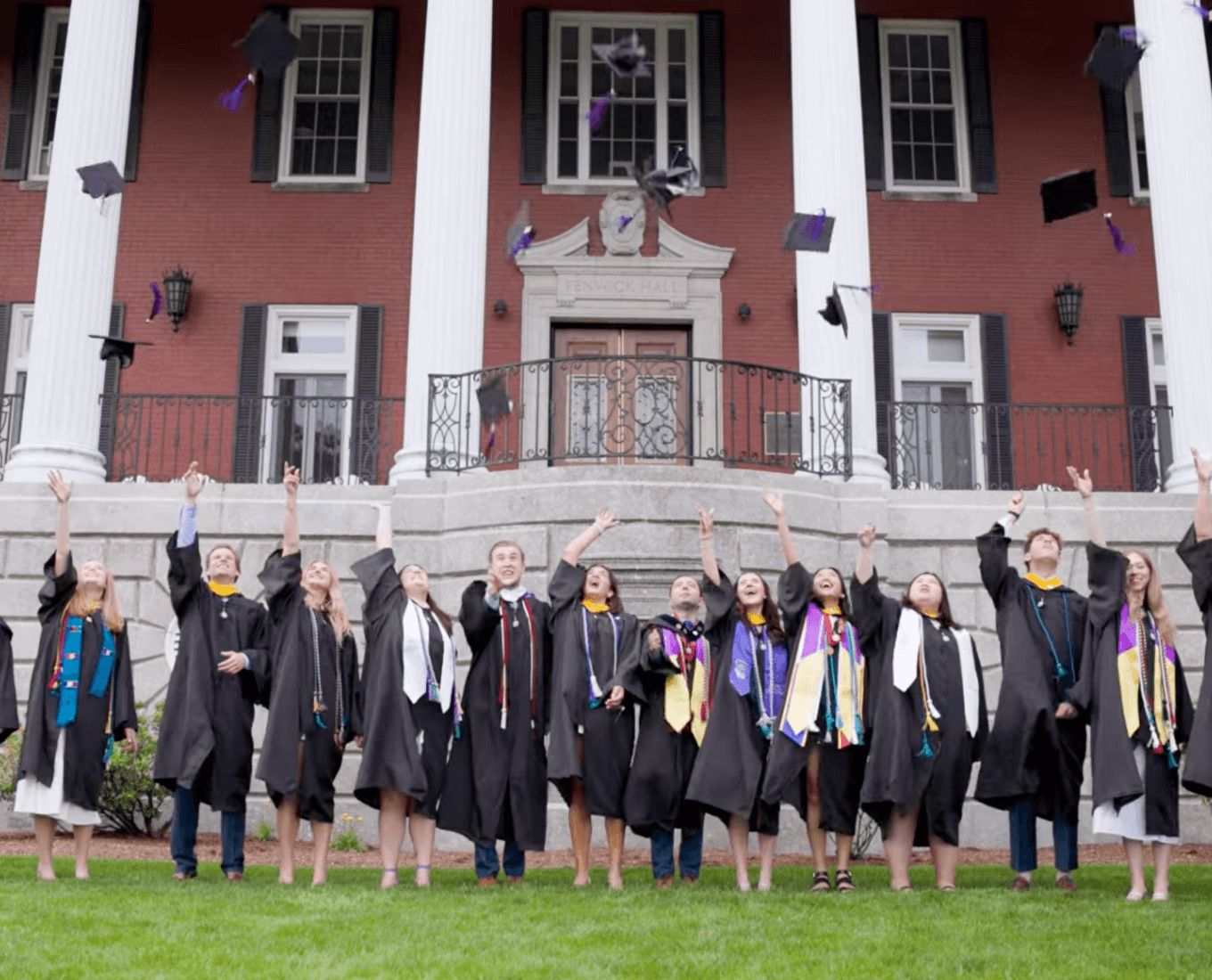 Graduates tossing their caps in front of Fenwick Porch