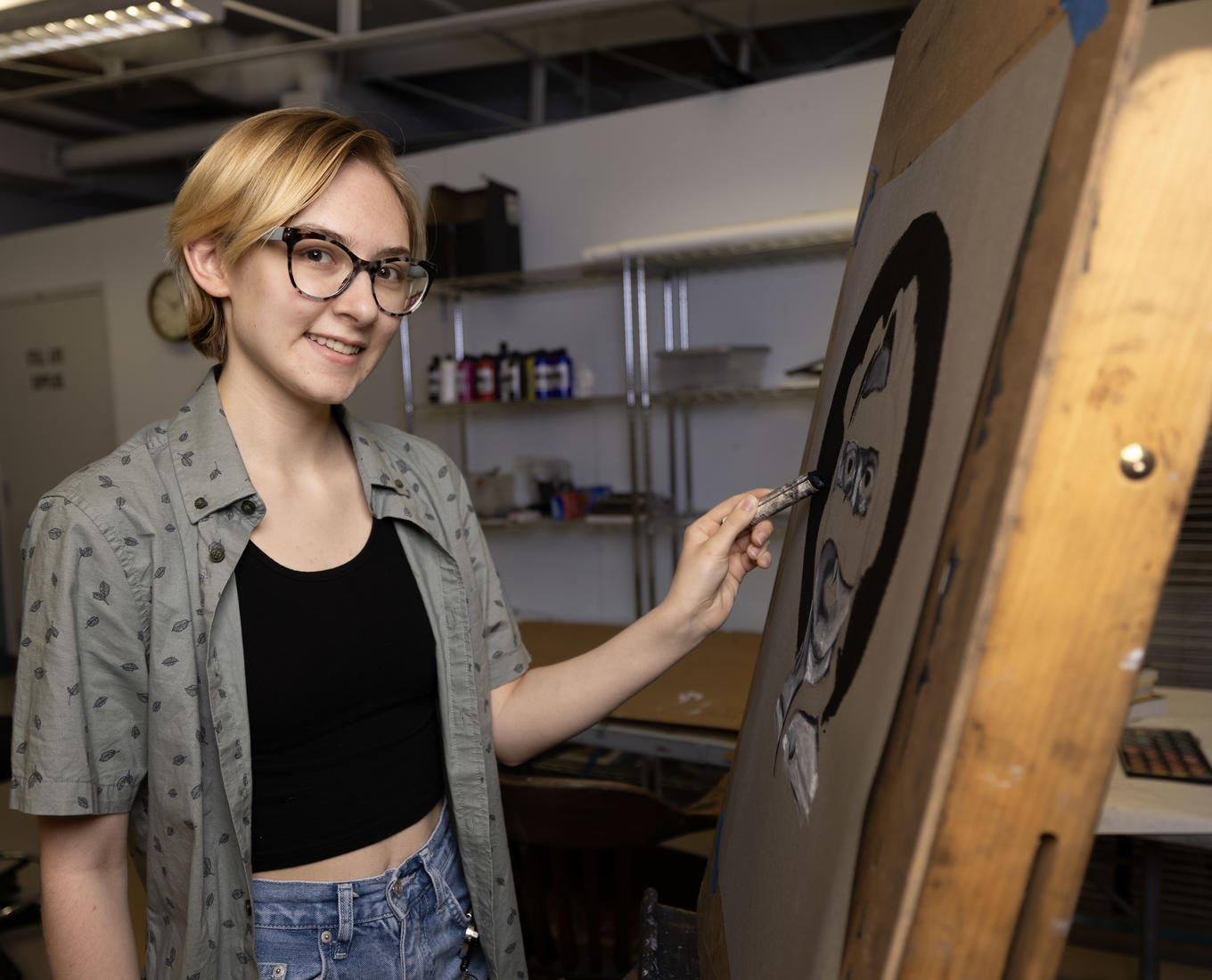 Young artist poses in front of drawing easel.