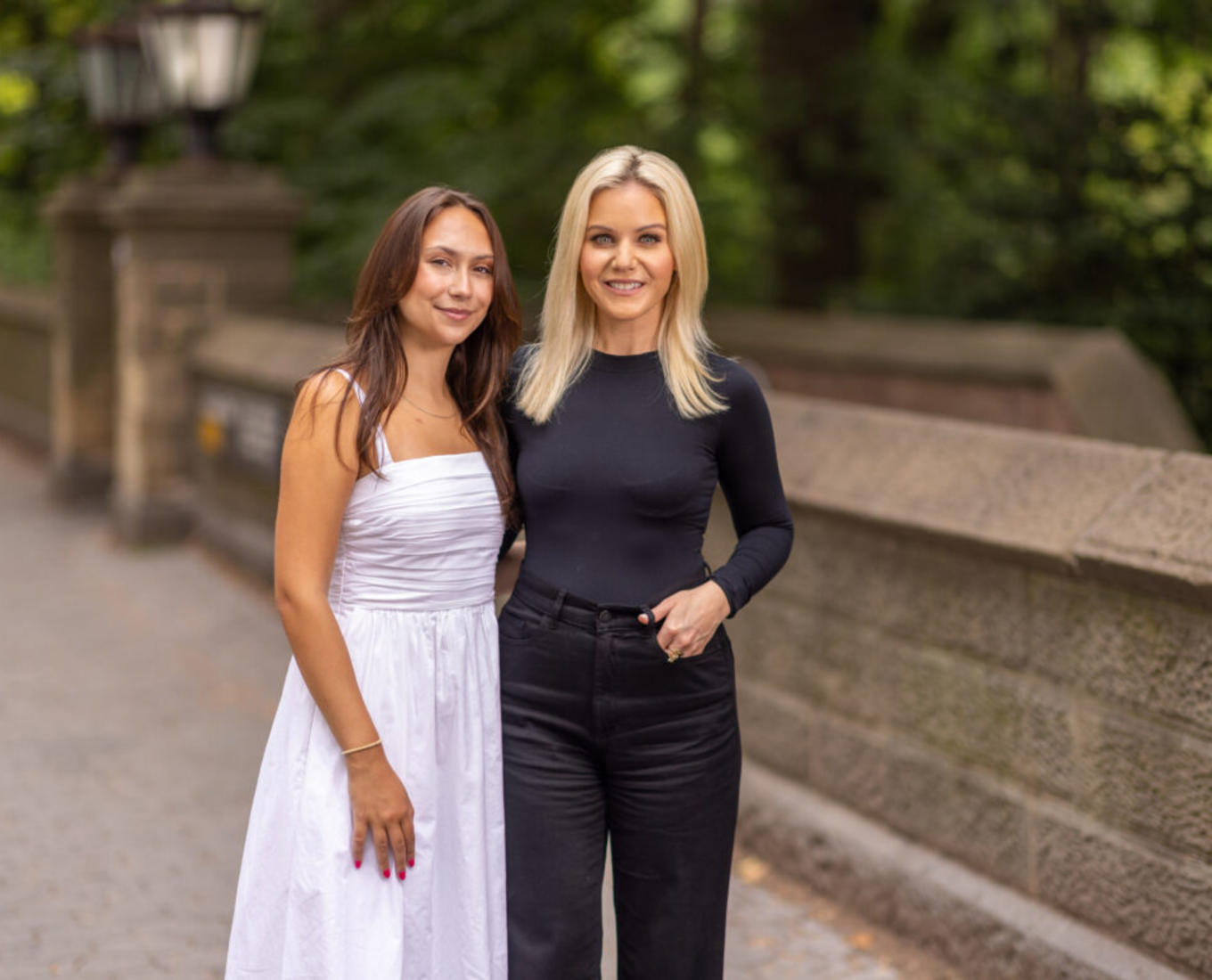 Two women stand together near park in New York City.