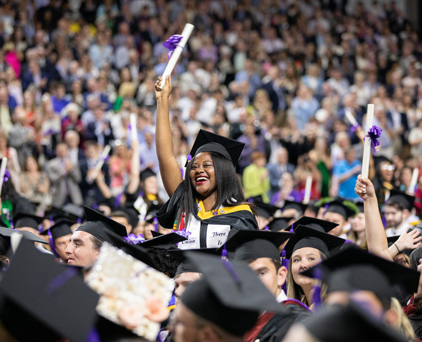 A graduating student waves her diploma at the 2019 Holy Cross graduation.