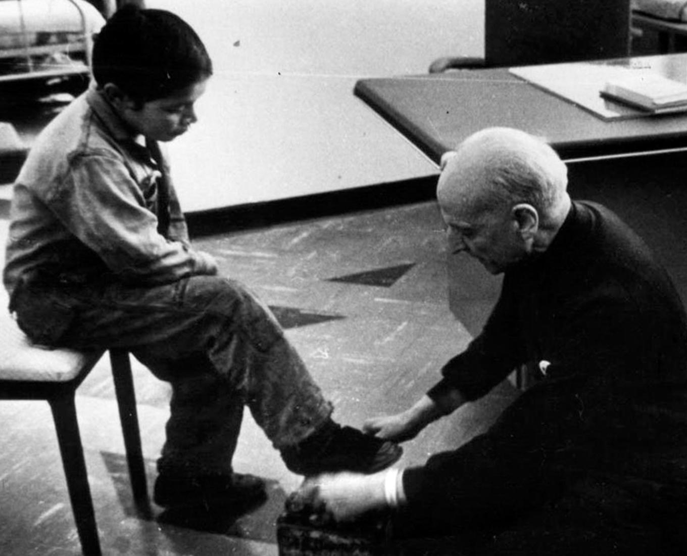 Man kneeling at the feet of a seated child.