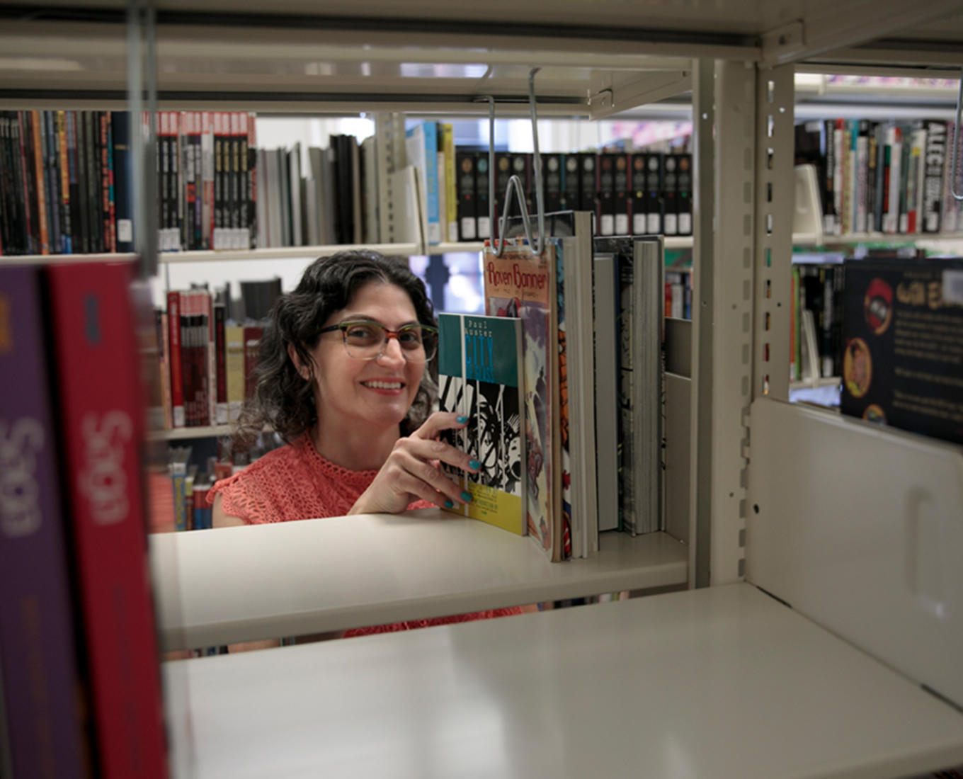 Woman reaching for a book on a library shelf