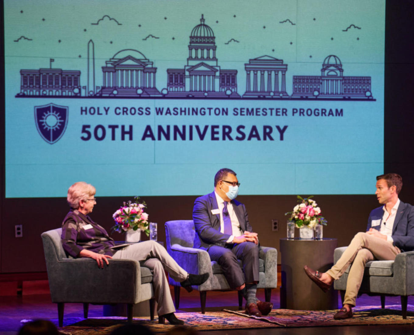 Jon Favreau, Holy Cross President Vincent Rougeau and Provost Margaret Freije sit on a stage