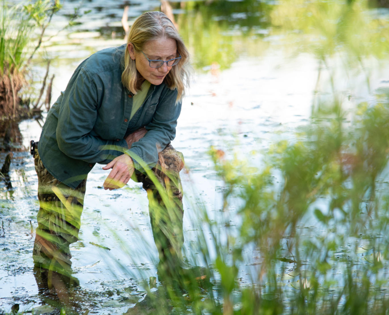 A woman stands in a shallow body of water.