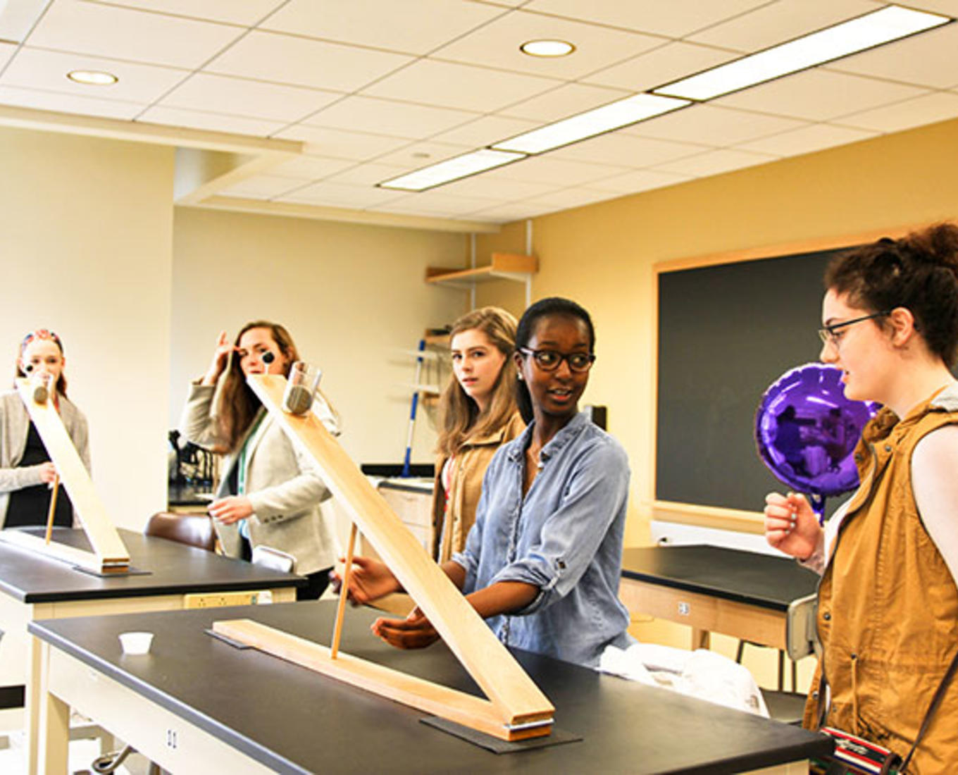 Students stand around a table with large pieces of wood