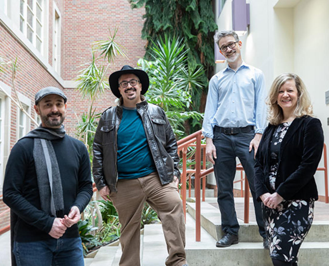 Ellis Jones, Jorge Santos, Jeremy Jones and Karen V Guth standing on stairs in an atrium filled with plants