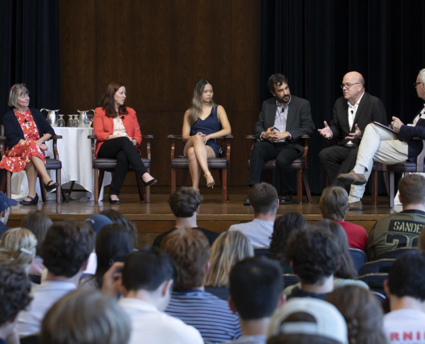 Group of people sit on stage as part of a symposium discussion.