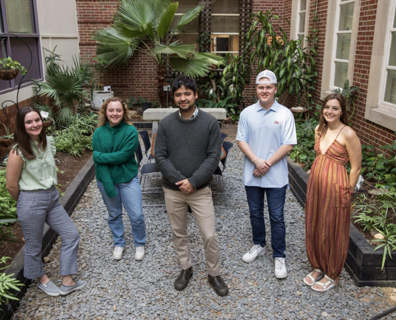 Four students stand with professor in the middle of botanic garden. 