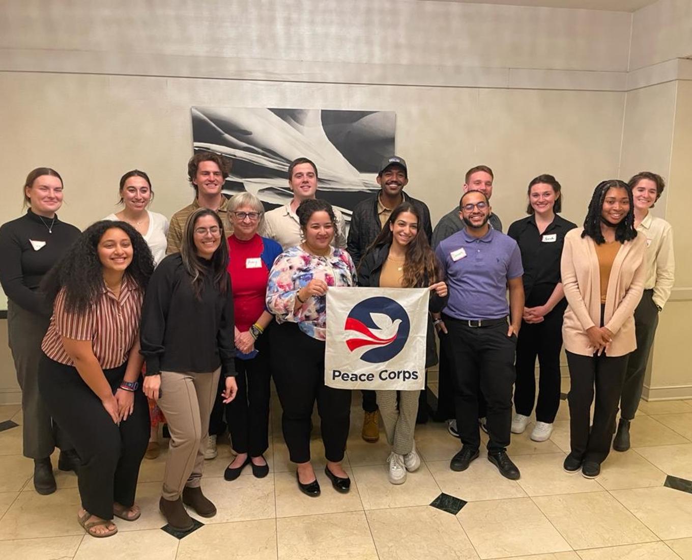 Peace Corps volunteers pose for a group photo inside a conference room.