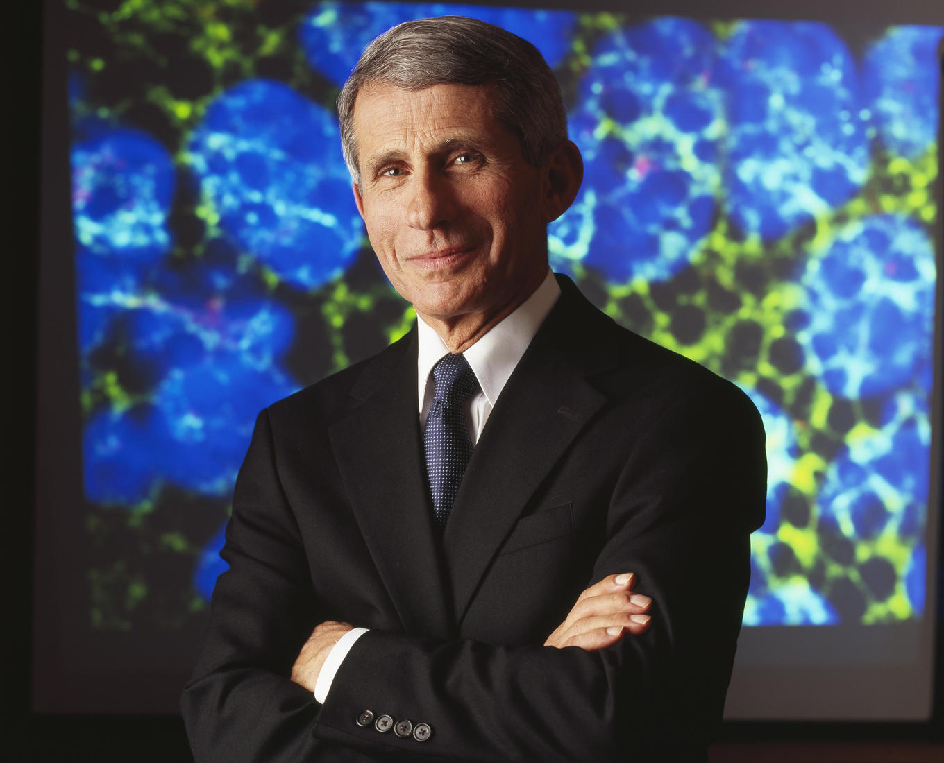 Dr. Anthony Fauci stands in front of a blue background