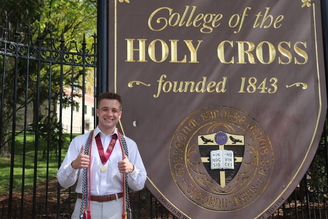 Kevin Hamilton standing next to the Holy Cross sign 