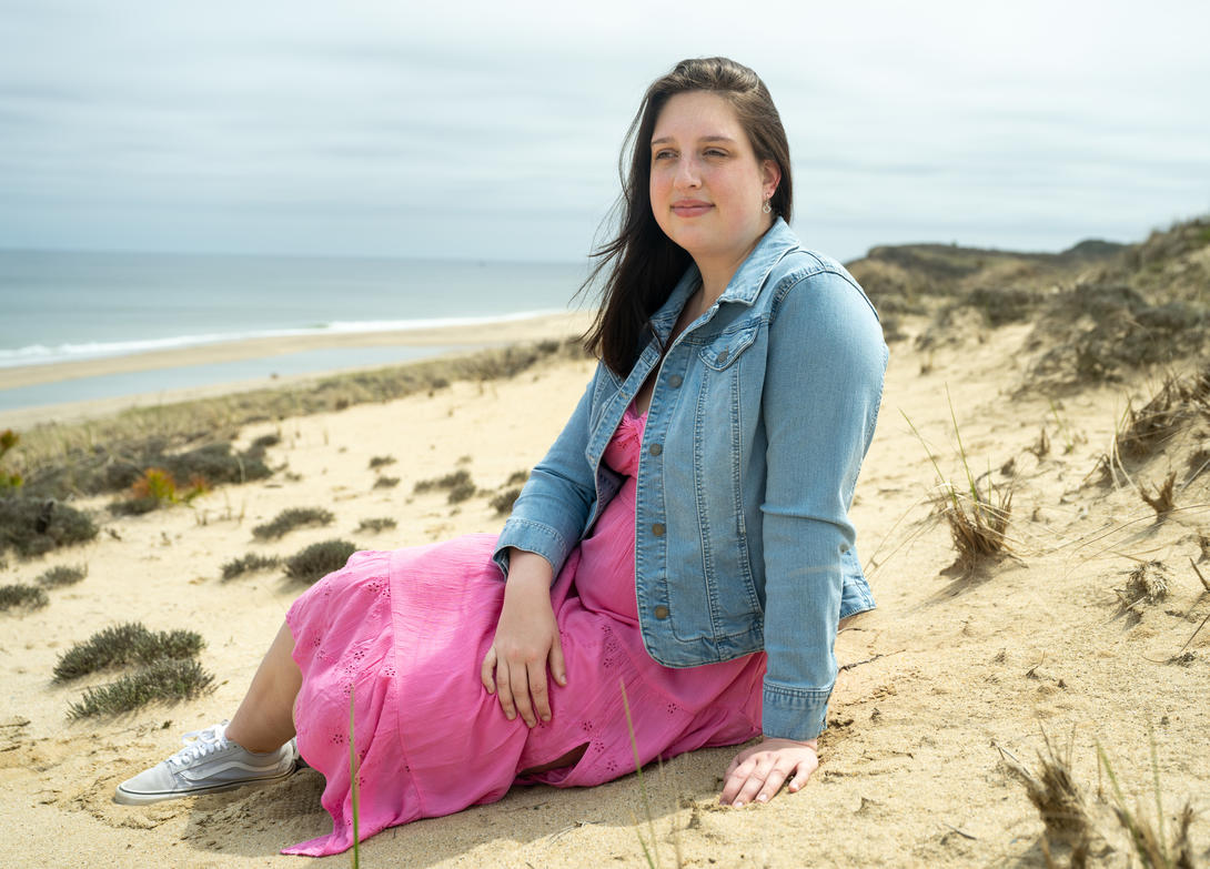 Young woman sitting on a sand dune at the beach.